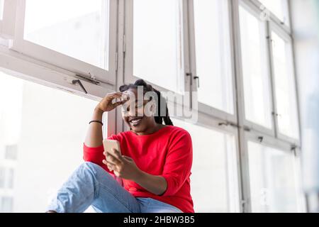 Young woman using smartphone in loft office Stock Photo
