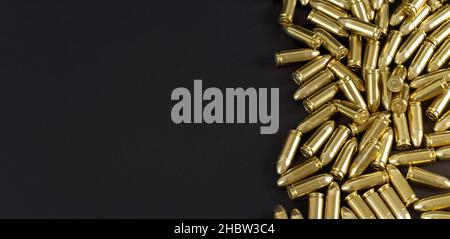 Many brass gun bullets on black table closeup view from above, space for text left side Stock Photo