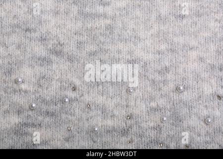 Knitted background. Light gray gentle wool background pattern. Background embroidered with beads Stock Photo