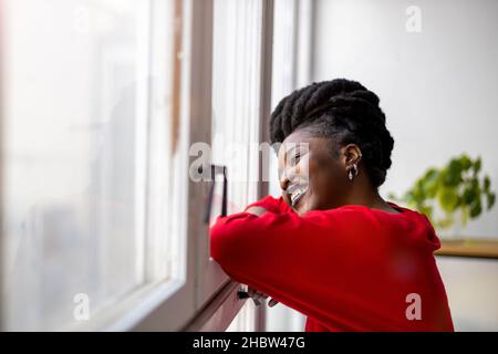 Young woman looking through window Stock Photo