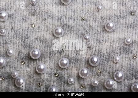 Knitted background. Light gray gentle wool background pattern. Background embroidered with beads Stock Photo
