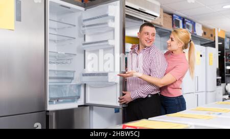 Couple chooses refrigerator in shop of household appliances Stock Photo