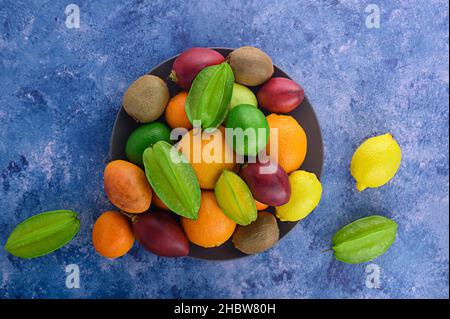 Citrus fruits on sapphirine background. Assorted citrus fruits and tamarillo. Kiwi on vintage table and other fruits. Copy space for your text. Fruits Stock Photo