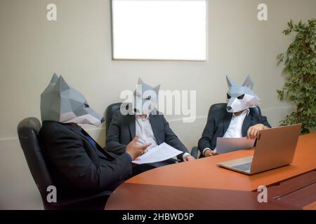 A group of business partners wearing wolf masks having a meeting in the office Stock Photo