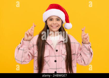 merry christmas. smiling kid in santa claus hat crossed fingers for luck. teen girl Stock Photo