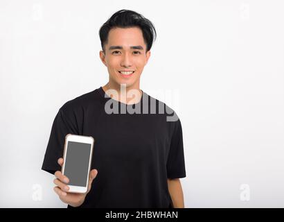 Asian hansome guy in black t-shirt isolated on white background, presenting smart phone blank screen Stock Photo