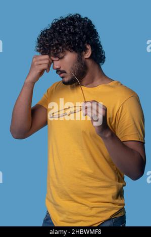 Exhausted dark-haired young man suffering from eyestrain Stock Photo