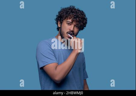 Tranquil young Indian man brushing his teeth Stock Photo