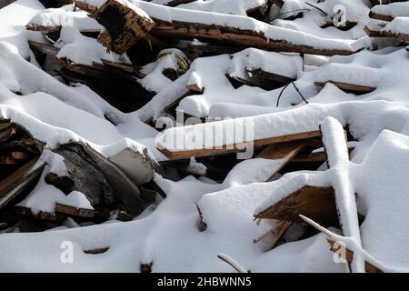 A pile of wood and metal debris from the demolition of an old building in Speculator, NY US covered in snow from a recent storm Stock Photo