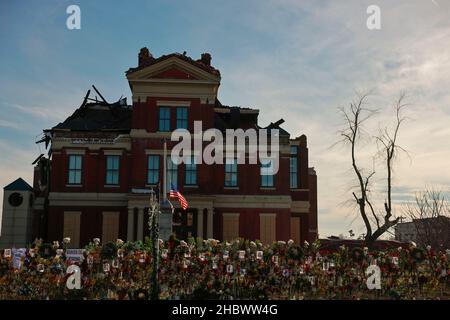 MAYFIELD, KENTUCKY - DECEMBER 20:  Flowers and photos of those who died are left at a makeshift memorial on a fence surrounding the Graves County courthouse, on December 20, 2021 in Mayfield, Kentucky.  Multiple nighttime tornadoes struck several Midwest states on December 10, causing widespread destruction and multiple casualties. Stock Photo