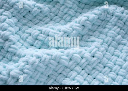 Background is handmade knitted blanket, close up of mint color Stock Photo