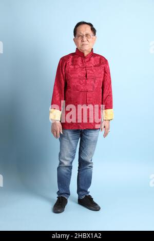 The senior Asian man wearing traditional Chinese shirt on the blue background. Stock Photo