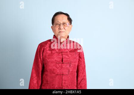 The senior Asian man wearing traditional Chinese shirt on the blue background. Stock Photo