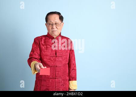 The senior Asian man wearing traditional Chinese shirt on the blue background. Stock Photo