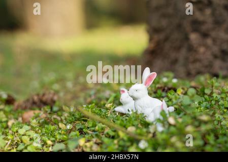 Cute Easter bunny figurine on a green moss of the forest. Spring seasonal Easter holiday background Stock Photo