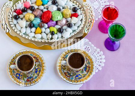 Colorful,Traditional Turkish Almond Candies and Chocolates in the metal tray with Turkish Coffee and liqueur.Celebration table of any festival. Stock Photo