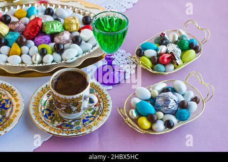 Colorful,Traditional Turkish Almond Candies and Chocolates in the metal tray with Turkish Coffee and liqueur.Celebration table of any festival. Stock Photo