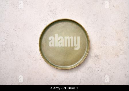 Empty green rustic ceramic plate on light textured marble background, flat lay, copy space Stock Photo