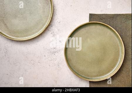 Two green plates with napkin on white textured background. Design concept, copy space Stock Photo