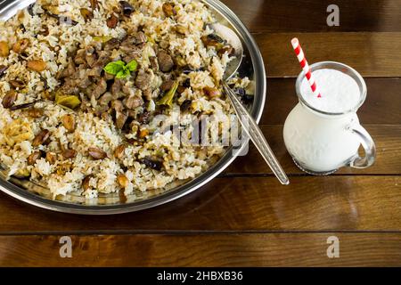 Traditional Turkish Sacrifice Festival Food braised meat Kavurma and pilaff in the large metal tray with big spoon and  traditional drink buttermilk Stock Photo