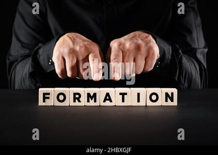 Business person hands pointing to the word formation on wooden blocks. Business job formation or education formation concept. Stock Photo
