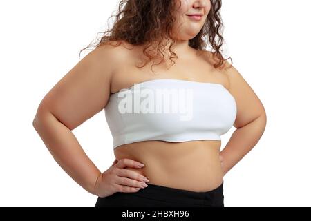 Cropped image of plus-size woman wearing white top and jeans posing isolated on white studio background. Stock Photo