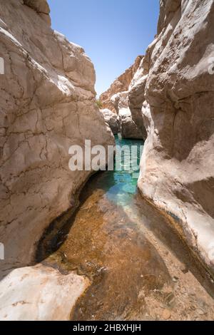 Small narrow white stone gorge with turquoise waters in Wadi Bani Khalid, Oman. Beautiful natural swimming pool in Arabian desert. Stock Photo