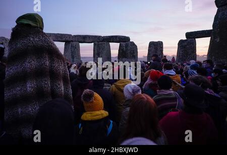 People take part in the winter solstice celebrations during sunrise at the Stonehenge prehistoric monument on Salisbury Plain in Wiltshire. Picture date: Wednesday December 22, 2021. Stock Photo