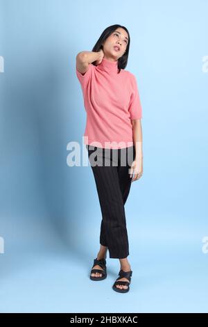 The young Asian woman wearing pink clothes standing on the blue background. Stock Photo