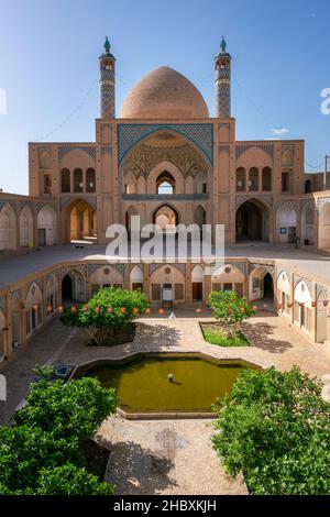 Kashan,Iran-04.08.2019: Courtyard, dome and minarets of Agha Bozorg Mosque in Kashan. Small garden in the middle of the courtyard. Stock Photo