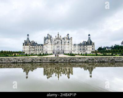 Wide angle view of Castle of Chambord in Loire valley, with its gardens, Cloudy day, water reflection, France Stock Photo