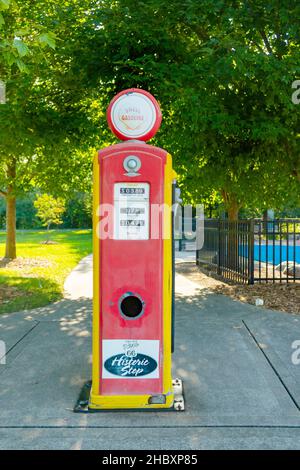 Vintage red and yellow Shell gasoline pump with Route 66 logo, set outdoors against a lush green background in a park setting Stock Photo