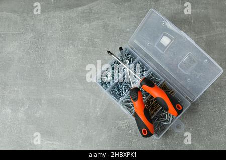 Box with screws and screwdrivers on gray textured background Stock Photo