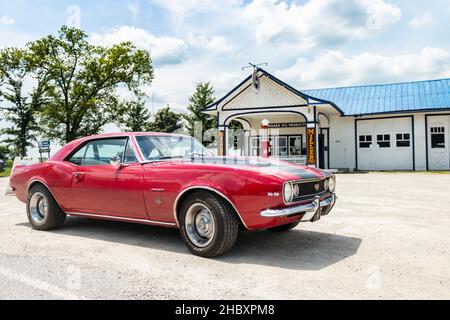 1967 red Chevrolet Camaro in front of vintage Standard Oil gas station  on Route 66 in Illinois at Odell Stock Photo