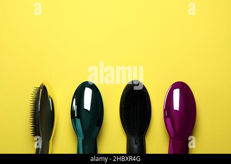 Colored plastic hair brushes on yellow background Stock Photo