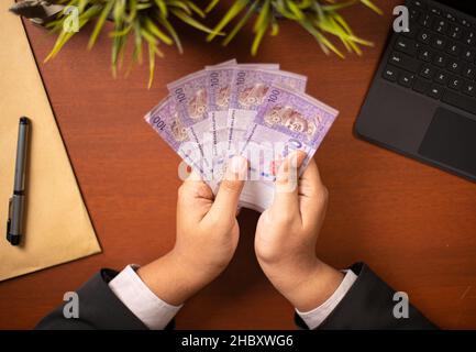 Businessman or CEO or Politician hands holding bribe money on an office desk. Venality, bribe, corruption concept. Stock Photo