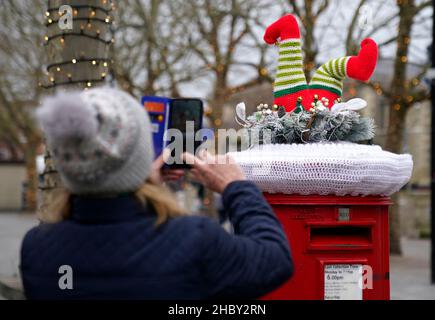 A person takes a photo of a festive yarn bomb on the top of a Royal Mail post box in Salisbury, Wiltshire. Picture date: Wednesday December 22, 2021. Stock Photo