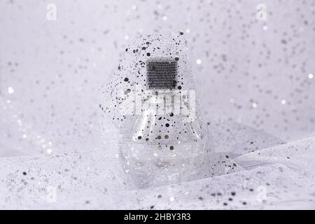 glass perfume bottle with silver sequins on light background Stock Photo