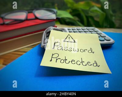 Password protected text written on a sticky note with books and calculator background. Stock Photo