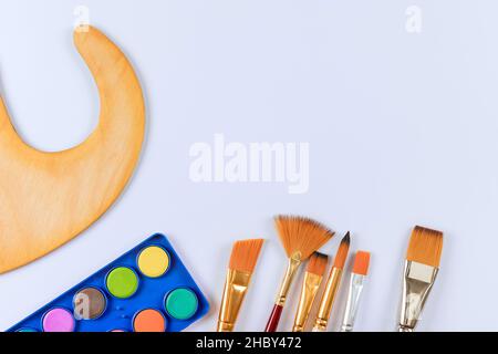 Closeup flat view on watercolor paints with painting brushes and wooden art palette Stock Photo