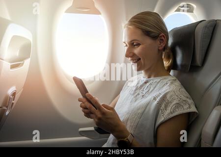 young woman using mobile phone during the flight in the airplane Stock Photo