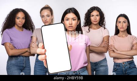 Serious ladies showing blank empty smartphone screen for mockup Stock Photo