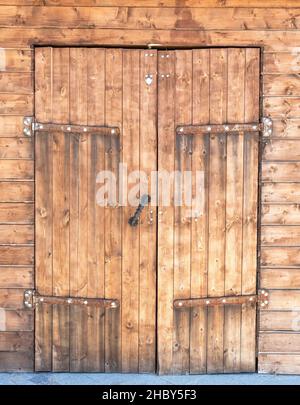 Old wooden gate with massive metal hinges Stock Photo
