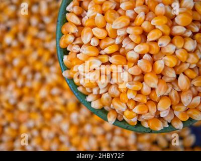Popcorn kernels in a green bowl, top view, selective focus Stock Photo