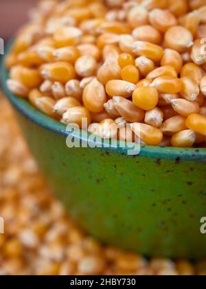 Popcorn kernels in a green bowl, selective focus Stock Photo