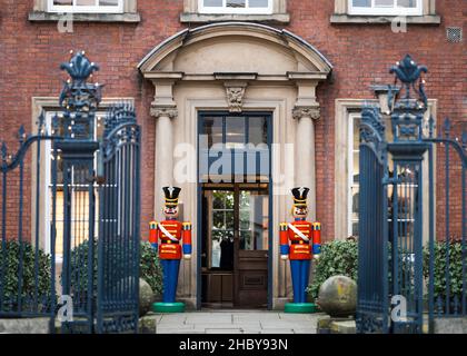 Bright coloured life size nut cracker Christmas decoration soldiers standing guard outside old building on shopping high street in red uniforms guard Stock Photo