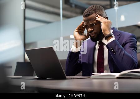 Concentrated black businessman solving business tasks, using computer Stock Photo