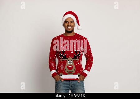 Happy black guy in Santa hat and sweater with deer Stock Photo