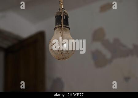 Dirty light bulb in socket hanging from the ceiling, Lost Place, Andalucia, Spain Stock Photo