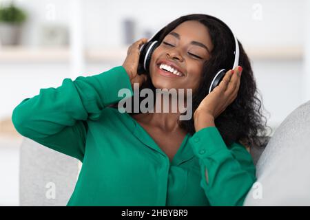 Relaxed african american woman listening to music, using headset Stock Photo